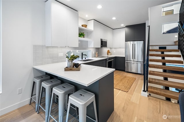 kitchen featuring white cabinetry, stainless steel appliances, a kitchen breakfast bar, and kitchen peninsula