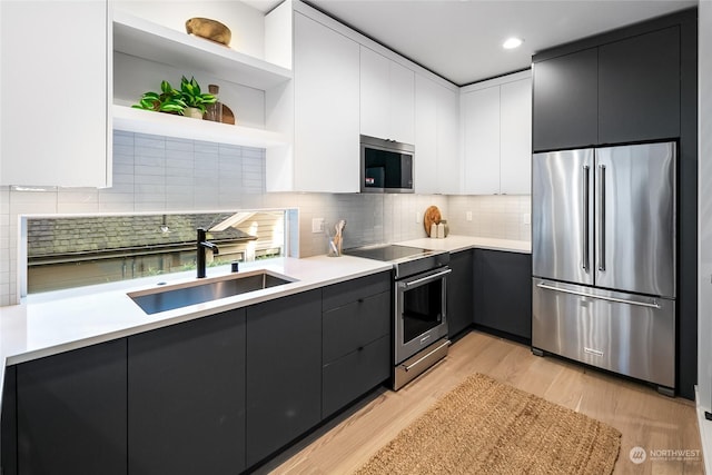 kitchen featuring sink, light hardwood / wood-style flooring, white cabinetry, stainless steel appliances, and decorative backsplash