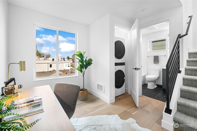 interior space with stacked washer / drying machine and light hardwood / wood-style flooring