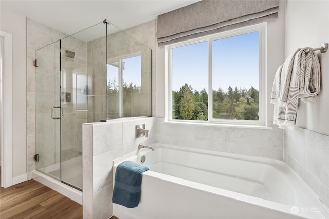 bathroom with wood-type flooring and shower with separate bathtub