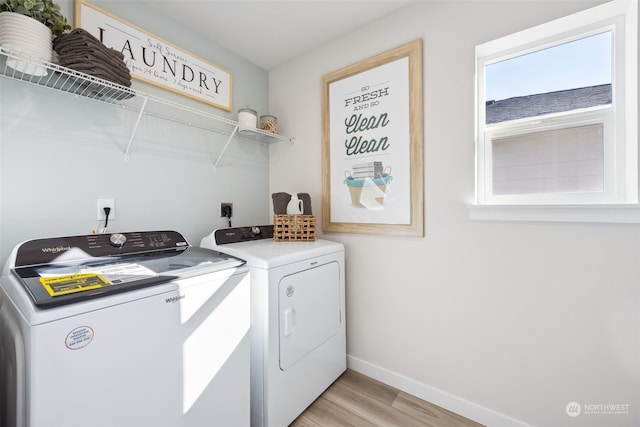 laundry room with washing machine and dryer and light wood-type flooring