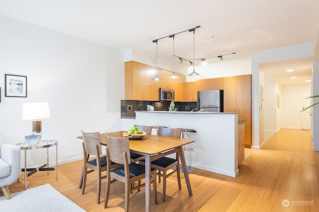 dining room with light wood-type flooring and rail lighting