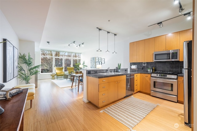 kitchen with decorative light fixtures, sink, appliances with stainless steel finishes, and kitchen peninsula