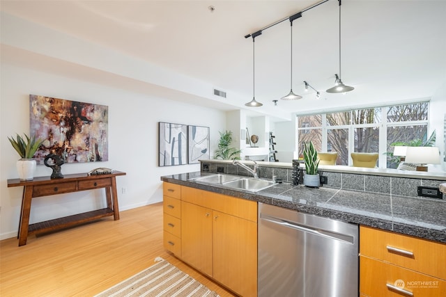 kitchen featuring stainless steel dishwasher, decorative light fixtures, sink, and light hardwood / wood-style flooring