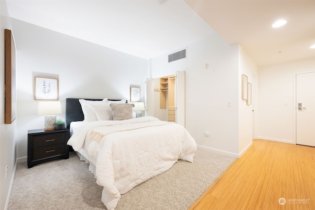 bedroom featuring light colored carpet, a closet, and a walk in closet