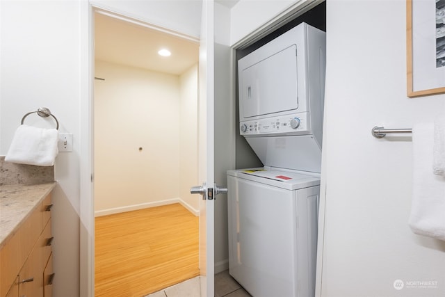 laundry room featuring light tile patterned floors and stacked washer / drying machine