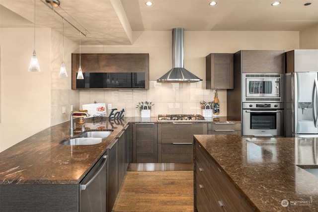 kitchen with sink, appliances with stainless steel finishes, dark stone counters, and wall chimney exhaust hood