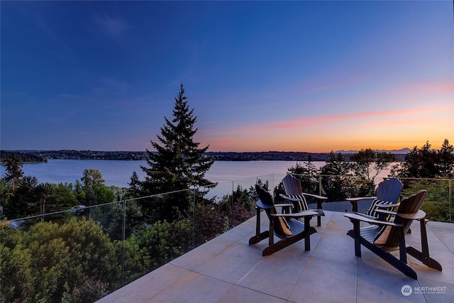 patio terrace at dusk featuring a water view