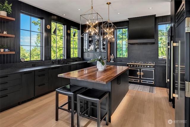 kitchen with a kitchen island, a breakfast bar, double oven range, hanging light fixtures, and wood counters