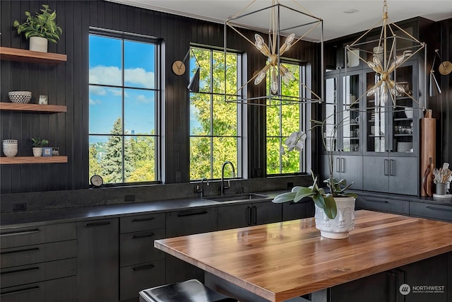 kitchen featuring decorative light fixtures, wooden counters, and sink