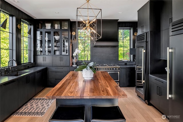 kitchen with light hardwood / wood-style floors, butcher block countertops, hanging light fixtures, high quality appliances, and sink