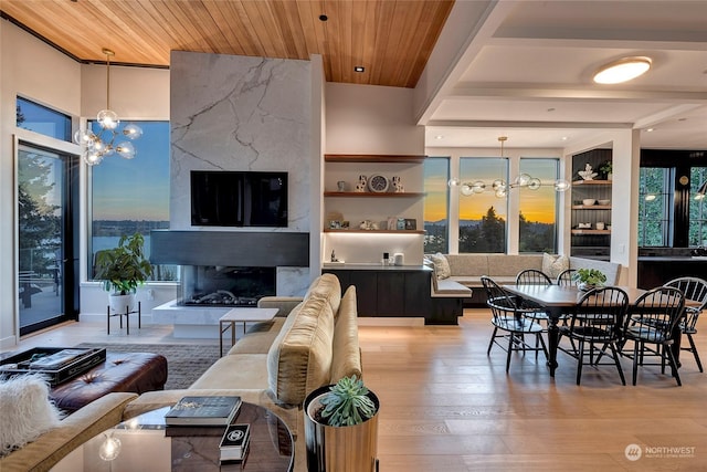 living room featuring wood-type flooring, a high end fireplace, wood ceiling, and an inviting chandelier