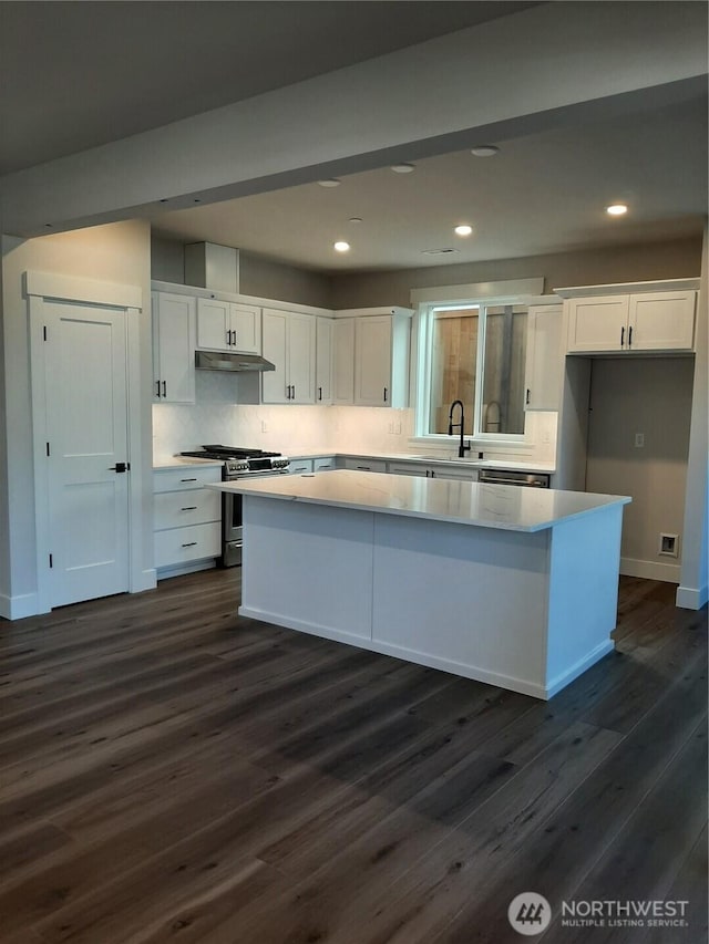 kitchen featuring white cabinetry, a center island, gas range, and under cabinet range hood