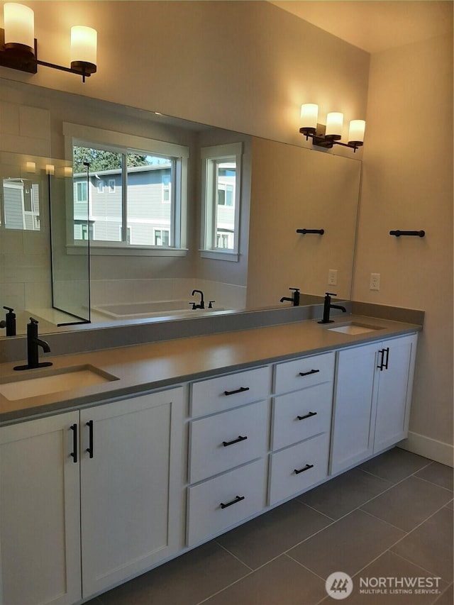 bathroom featuring double vanity, tiled shower, a sink, and tile patterned floors