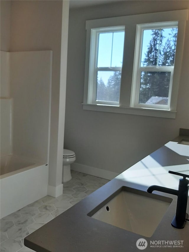 bathroom with shower / bathing tub combination, vanity, toilet, and baseboards