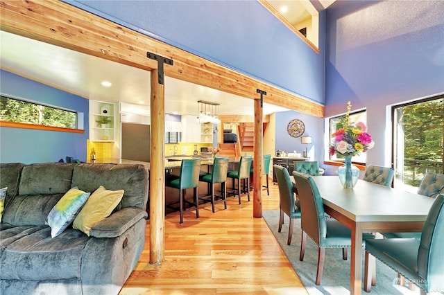 dining space featuring light wood-type flooring, built in features, a high ceiling, and a barn door