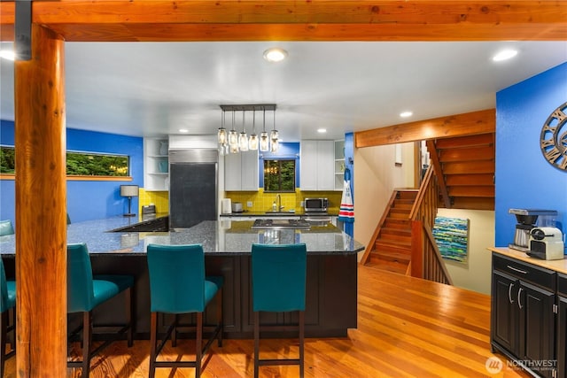 6520 E Mercer Way, Mercer Island, WA 98040 - kitchen featuring open shelves, light wood-style floors, dark stone countertops, a breakfast bar area, and white cabinets