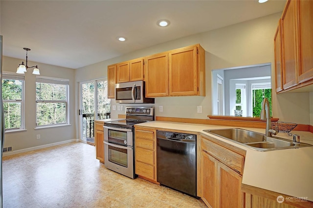 kitchen with appliances with stainless steel finishes, sink, pendant lighting, and light brown cabinetry