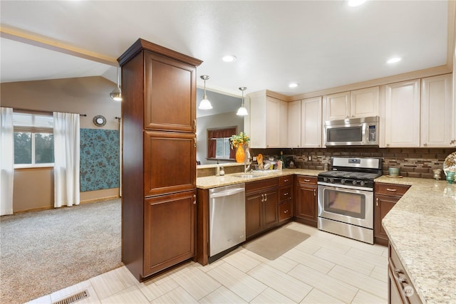 kitchen featuring decorative light fixtures, lofted ceiling, sink, light colored carpet, and stainless steel appliances