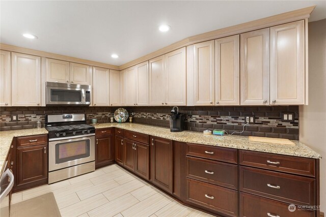 kitchen featuring light stone counters, appliances with stainless steel finishes, decorative backsplash, and cream cabinetry