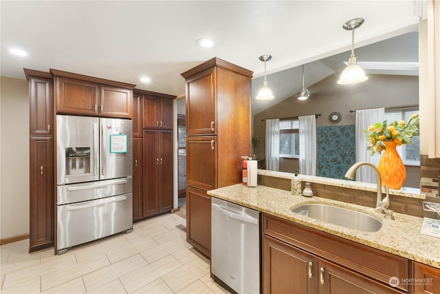 kitchen featuring sink, light stone counters, vaulted ceiling, hanging light fixtures, and stainless steel appliances