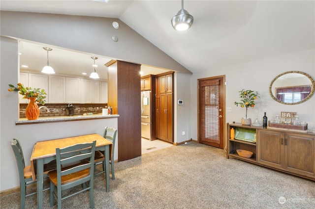 kitchen with pendant lighting, tasteful backsplash, white fridge with ice dispenser, vaulted ceiling, and light colored carpet