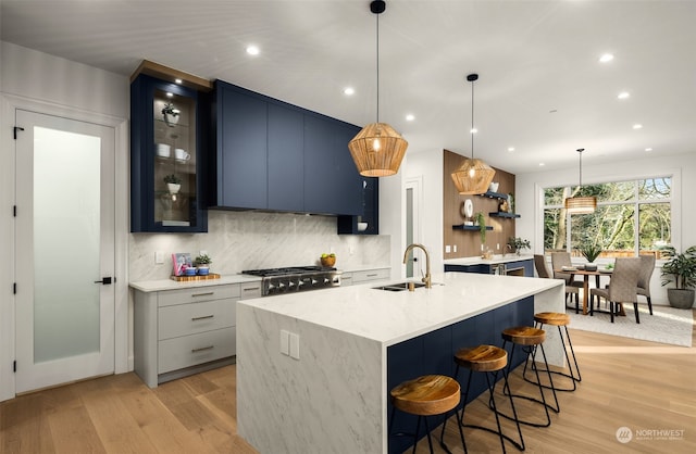 kitchen featuring sink, light wood-type flooring, blue cabinetry, and tasteful backsplash