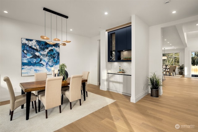 dining space featuring indoor bar and light wood-type flooring