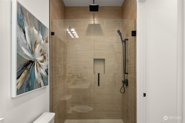 bathroom featuring a shower with shower door and toilet