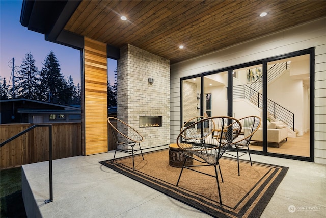 patio terrace at dusk featuring an outdoor stone fireplace