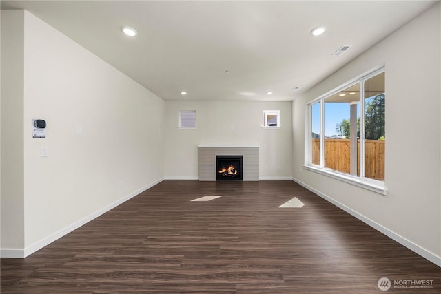 17920 139th Pl E, Puyallup, WA 98374 - unfurnished living room featuring a warm lit fireplace, recessed lighting, baseboards, and dark wood-type flooring