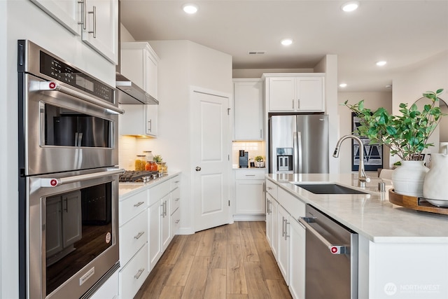 17920 139th Pl E, Puyallup, WA 98374 - kitchen with stainless steel appliances, a sink, light wood-style floors, white cabinetry, and backsplash