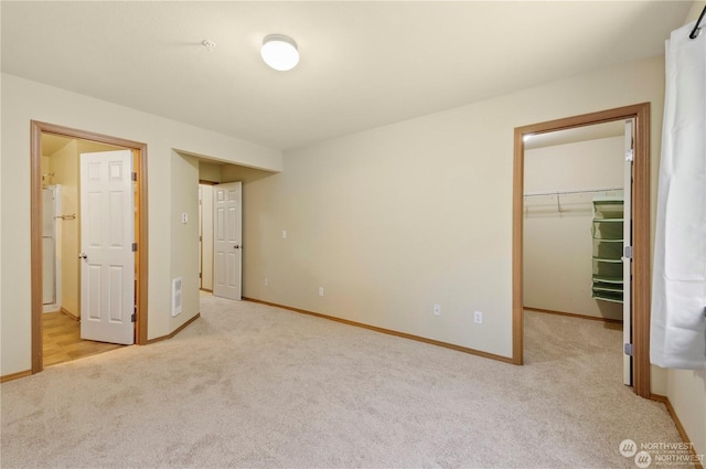 unfurnished bedroom featuring a spacious closet, light carpet, and a closet