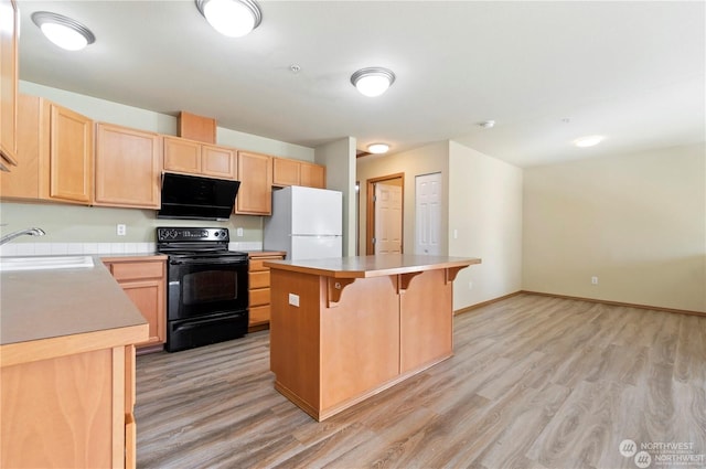 kitchen featuring a breakfast bar, sink, black electric range, a kitchen island, and white fridge