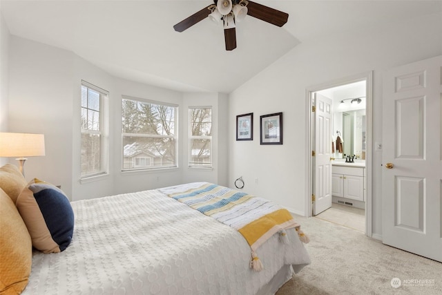 bedroom featuring lofted ceiling, sink, ensuite bath, light carpet, and ceiling fan