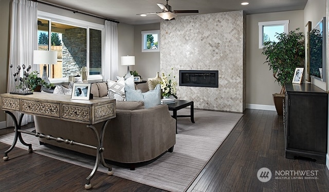 living room featuring ceiling fan, dark hardwood / wood-style flooring, and a fireplace