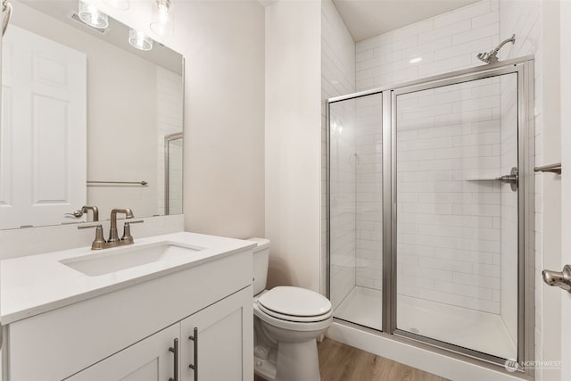 bathroom with hardwood / wood-style floors, an enclosed shower, vanity, and toilet