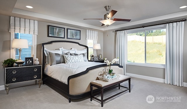 carpeted bedroom featuring ceiling fan and a raised ceiling