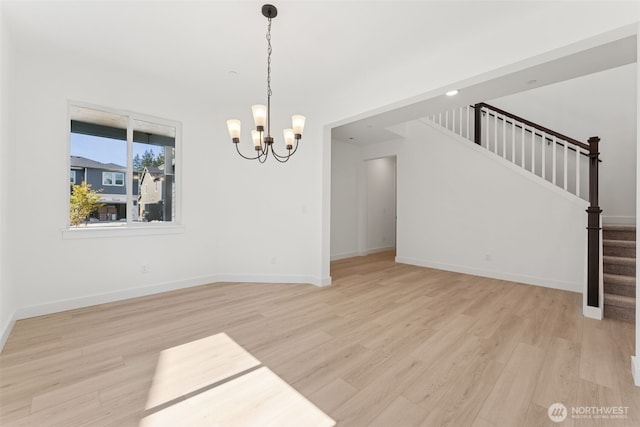 unfurnished dining area with stairway, baseboards, an inviting chandelier, and light wood finished floors