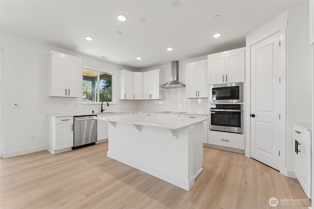 kitchen with wall chimney range hood, decorative backsplash, a breakfast bar area, a sink, and stainless steel appliances