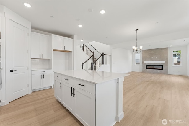 kitchen with white cabinets, backsplash, light wood finished floors, and light countertops