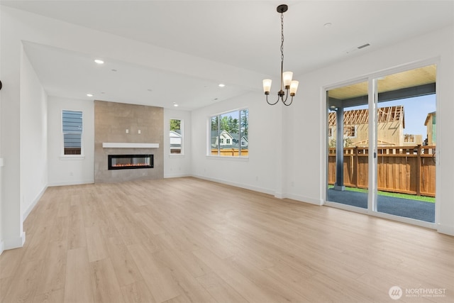 unfurnished living room featuring a fireplace, baseboards, recessed lighting, light wood finished floors, and a notable chandelier