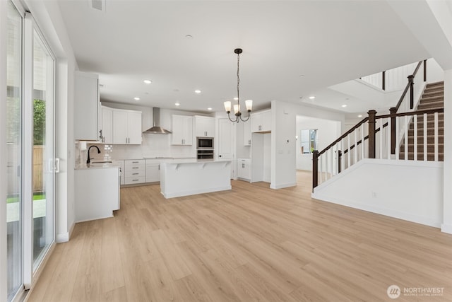 kitchen featuring stainless steel appliances, a healthy amount of sunlight, a sink, and wall chimney exhaust hood