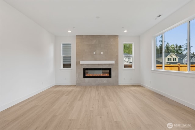 unfurnished living room featuring recessed lighting, baseboards, light wood-type flooring, and a tile fireplace