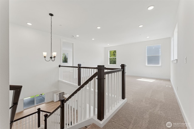 hallway with an upstairs landing, carpet floors, baseboards, a notable chandelier, and recessed lighting