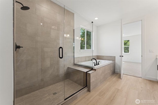 full bathroom featuring a bath, baseboards, a stall shower, and wood finished floors