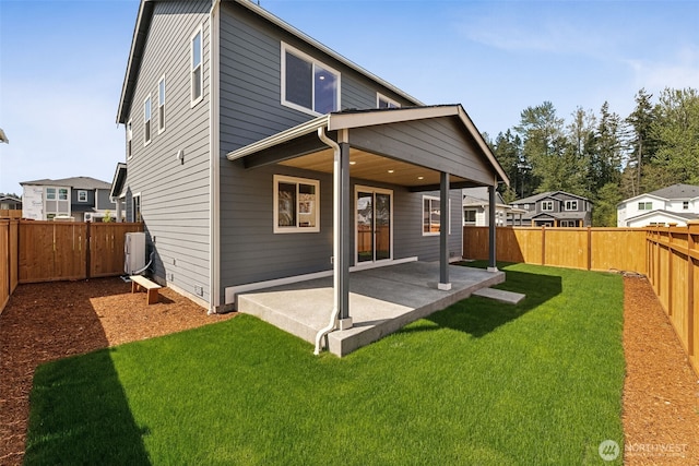 rear view of property featuring a fenced backyard, a patio area, and a yard