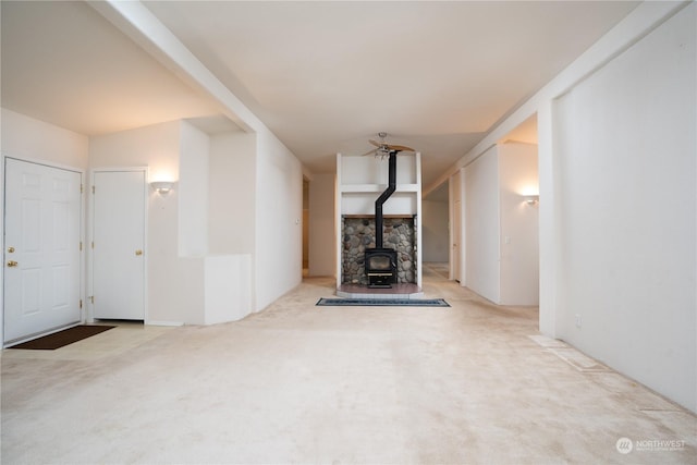 unfurnished living room featuring light carpet and a wood stove