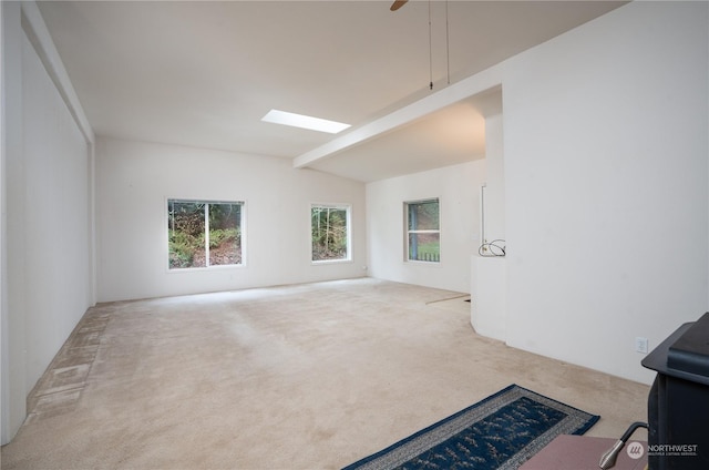 carpeted spare room featuring ceiling fan and lofted ceiling with beams