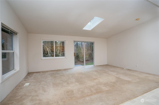 carpeted spare room with lofted ceiling with skylight